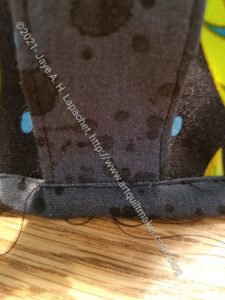 Zipper tabs sewn under binding