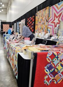 Victoria Findlay Wolfe with quilts in booth